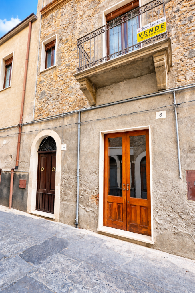 Facciata mediterranea con cartello vendesi